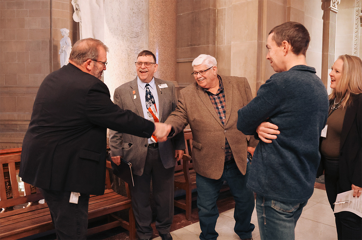 A group of Indiana Farm Bureau members shaking hands with a legislator.