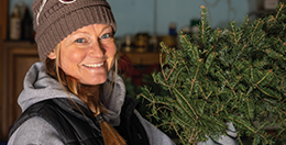 A woman smiling holding up a Christmas wreath.